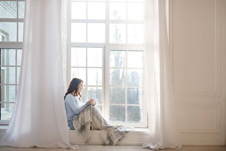 Morning harmony. Dark-haired young woman looking out the window
