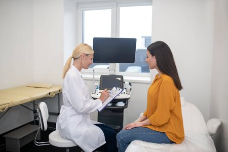 Doctor and patient. Blond doctor talking to her young dark-haired patient after ultrasonic procedureの写真素材