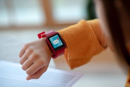 Smartwatch. Close up of girls wrist with smartwatch on red watchband