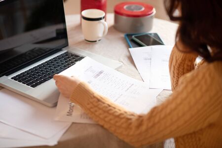 Financial difficulties. Woman with long hair looking at the bill feeling upsetの写真素材