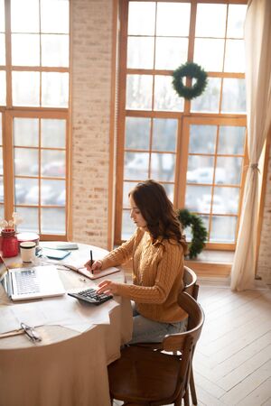 Busy with work. Dark-haired young woman in sweater looking busyの写真素材