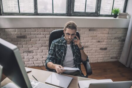 On the call. Young man in eyeglasses speaking on the phoneの写真素材