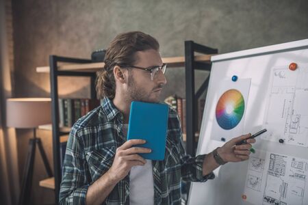 Presentation. Young handsome man in eyeglasses standing near white board