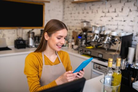 Barista with a tablet. Smilling cafe employee using the tablet for her work