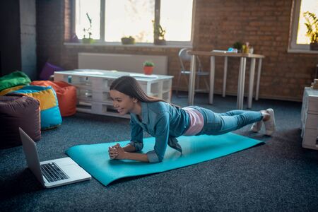 Video lesson. Nice young woman looking at the laptop screen while watching a workout tutorial