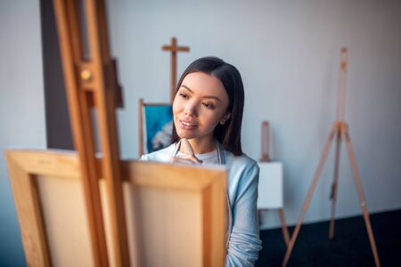 Favourite hobby. Joyful young woman being involved in painting while standing in the dance studioの写真素材