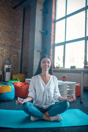 Meditation pose. Joyful nice woman relaxing while sitting on the yoga man in the meditation poseの写真素材