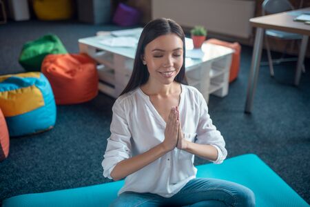Very relaxing. Nice pretty woman sitting with her eyes closed while practicing yoga at homeの写真素材