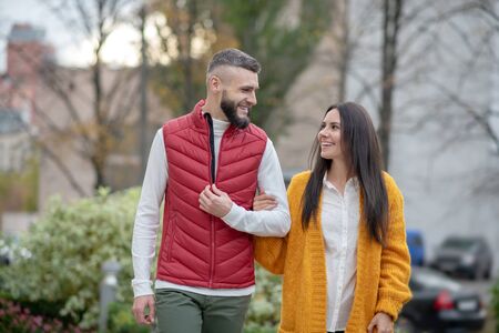 First date. Positive young couple looking at each other while having a walk togetherの写真素材