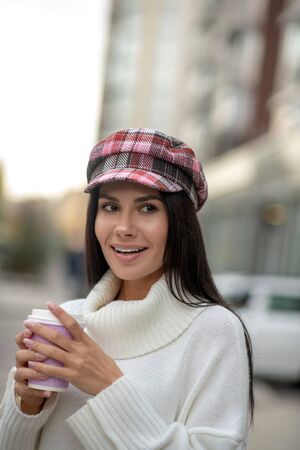 Takeaway coffee. Pretty attractive woman holding a cup while drinking coffee on the street