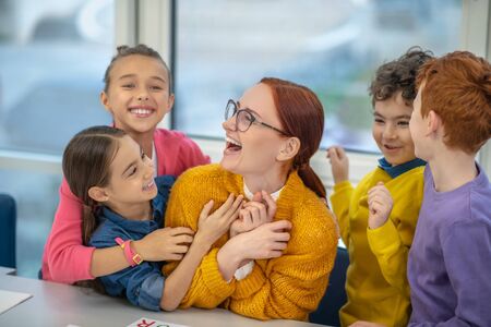 Good relations with the teacher. Happy pupils hugging their favourite teacherの写真素材