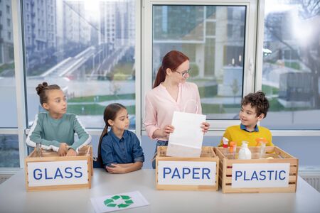 Eco-education. The teacher explaining to pupils how to sort the wasteの写真素材