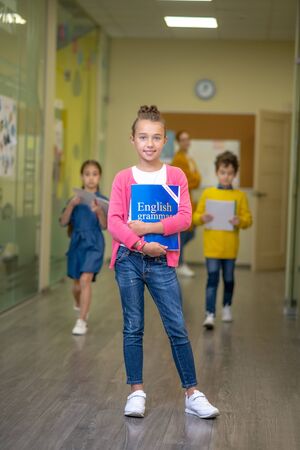First to go. Pretty schoolgirl standing in front of her running classmates in the school corridorの写真素材