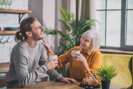 Coffee in the morning. Grey-haired mom and her son having coffee togetherの写真素材