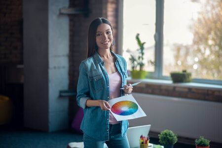 Creative designer. Pleasant nice woman standing with a colour scheme while working as a creative designerの写真素材