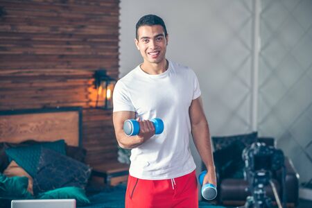 Good mood. Strong dark-haired man in red shorts looking good while having a workoutの写真素材