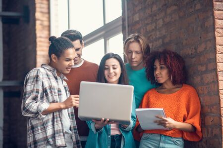 Smart students discussing. Group of smart students discussing and making notes while watching webinarの写真素材