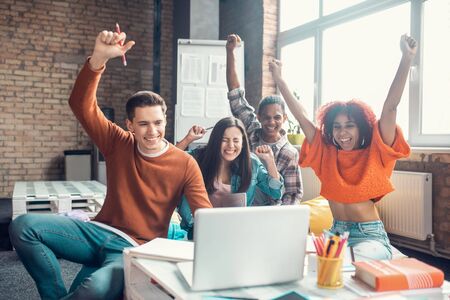 Students feeling happy. Cheerful beaming students feeling happy while watching webinar togetherの写真素材