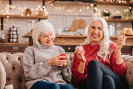 Skin care. Two grey-haired pleasant cute ladies discusing new anti-aging creamsの写真素材