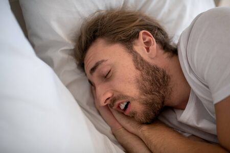 Night dream. A relaxed man sleeping deeply in his bedの写真素材