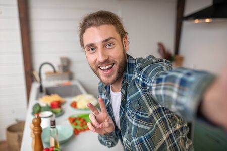Boasting with a new meal. A smiling man making selfie on his kitchenの写真素材