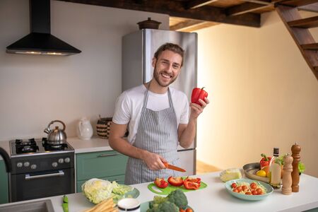 Cutting pepper. A smiling cook making a new dish with pepperの写真素材