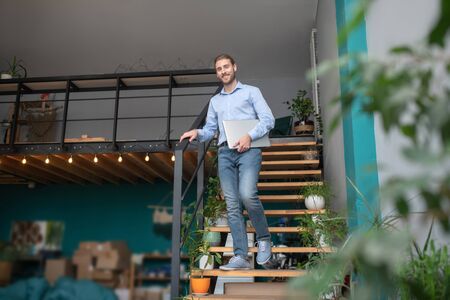 Having a workday. A man standing on stairs holding his computer