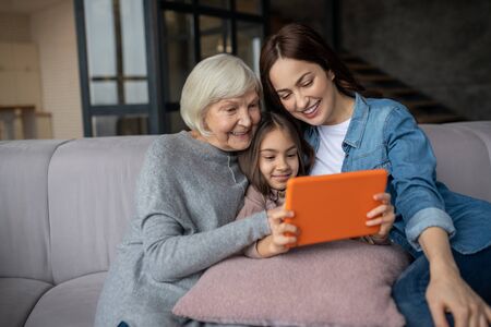 Interesting video. Grandmother mom and a little girl sitting at home on the couch close to each...
