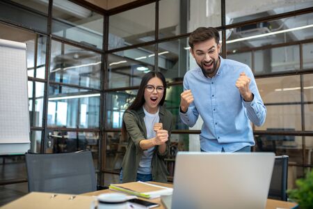 We did it. Tall young man and his female colleague feeling successful in the office