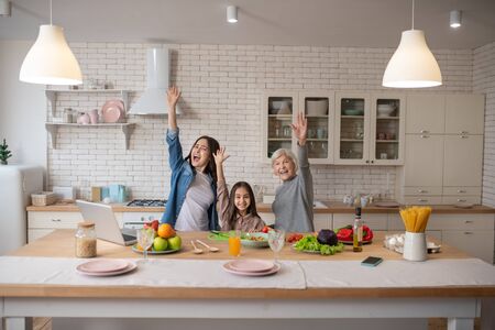 Happy people. Mom, grandmother, daughter are in the morning in the kitchen, preparing a healthy...