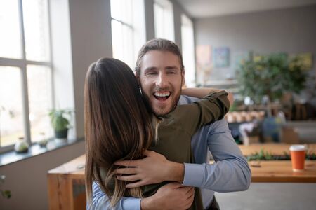 Hugging strongly. A smiling bearded man hugging his female friendの写真素材