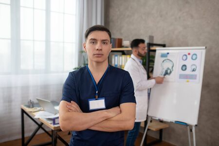 At work. Dark-haired young doctor standing in the middle of the room