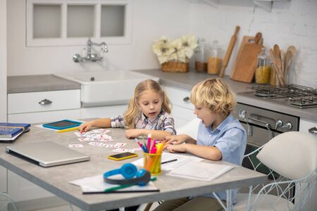 New knowledge. Two blond kids playing with letter cards and looking concentratedの写真素材