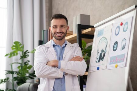 Positive vibes. Young bearded doctor in a white robe looking positiveの写真素材