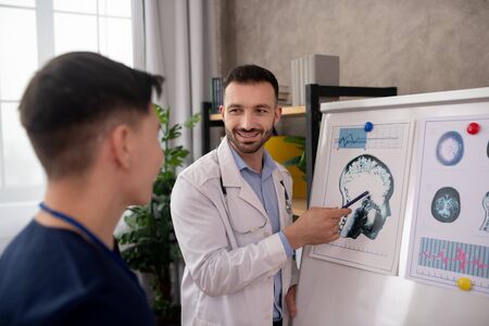 Important details. Bearded doctor explaining medical case details to his colleague