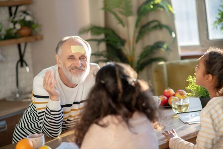 Family together. Grey-haired man having great time his granddaughters
