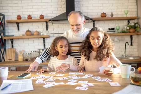 Interracial family. Bearded grey-haired man and two dark-skinned girls spending time togetherの写真素材