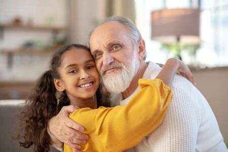 Hugs. Grey-haired man and a dark-skinned girl hugging each other