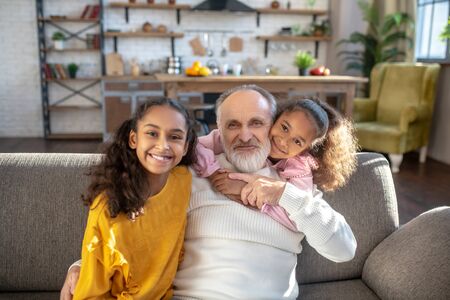 Together. Two dark-skinned sisters sitting next to their granddad