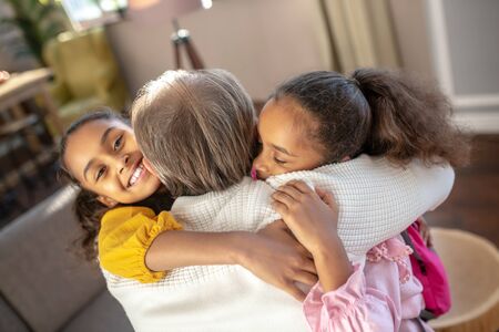 Meeting granddad. Bearded granddad hugging his granddaughters and feeling amazingの写真素材