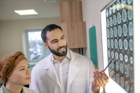 MRI results. Bearded young doctor explaining MRI results to the patient