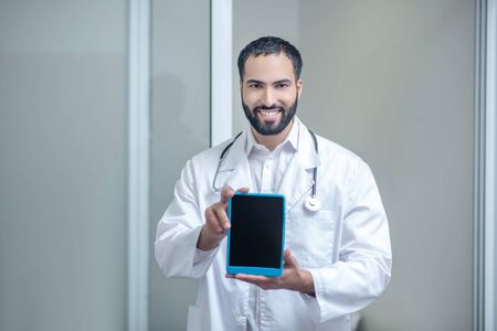 Device. Male doctor in a white robe holding a tablet in his handsの写真素材
