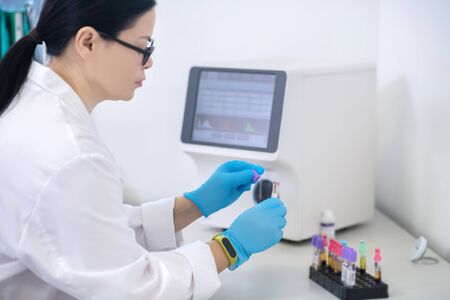 Samples. Technician in blue gloves holding samples with blood