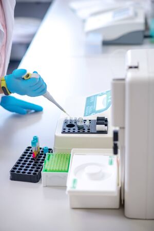 Drop of blood. Technician in blue gloves holding pipette in handの写真素材