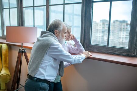 Remembering the past. Thoughtful couple of seniors looking at the windowの写真素材