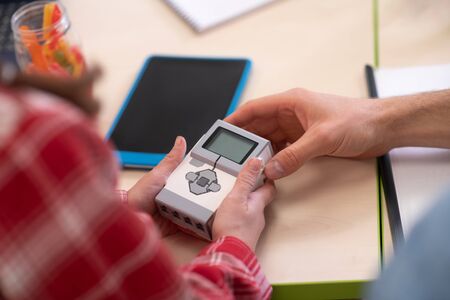 School classroom. Male teacher hands and girl hands holding control unit