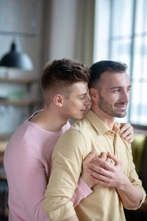 Happy together. Young gay couple standing in the room and huggingの写真素材