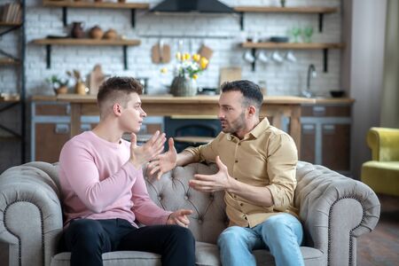 Argument. Two men sitting on the sofa having an argumentの写真素材