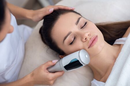 Facial massage. Specialist doing ultrasound facial massage for her young beautiful patient