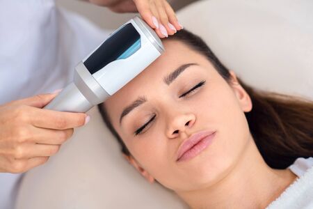 Enjoying massage. Close up of young appealing woman enjoying ultrasound facial massageの写真素材